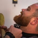 barber trimming a beard on a redhead