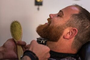 barber trimming a beard on a redhead