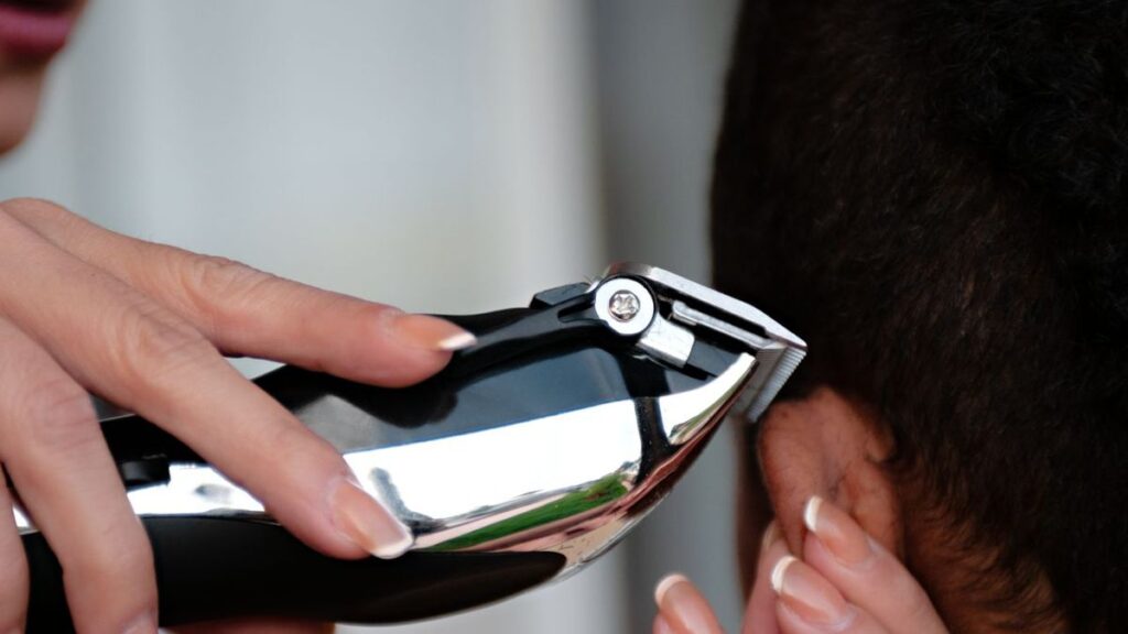 Andis ReVite Review: Is It Worth Buying in 2026? 1 Hand holding a chrome cordless hair clipper against the side of a client's head