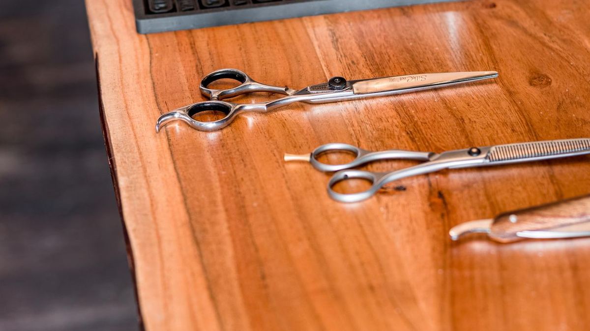 Best Barber Gifts From $50 to $100 in 2026 2 Barber scissors and clippers laid out on a rubber mat on a wooden station table