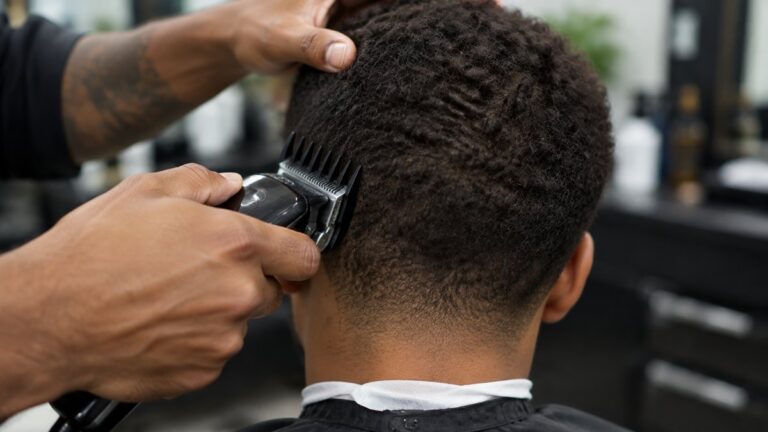 Barber using a guarded clipper on short textured curly hair